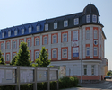 Zdjęcie przedstawia budynek Starostwa Powiatowego w Świdwinie, na pierwszym planie urzędowe tablice informacyjne.                                                                                       