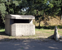 Widok na betonowy bunkier wraz z zielonym otoczeniem                                                                                                                                                    