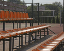 Zdjęcie przedstawia zbliżenie na trybuny kompleksu boisk Orlik w Świdwinie. W tle boisko do koszykówki i siatkówki.                                                                                     