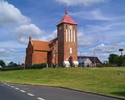 Zdjęcie przedstawia kościół pw. Matki Boskiej Królowej Polski w Tychowie widoczny z głównej drogi w miejscowości.                                                                                       