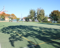 Na zdjęciu widać sztuczną murawę boiska do piłki nożnej i ręcznej, widać też zamontowane kosze do piłki koszykowej.                                                                                     