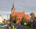Zdjęcie przedstawia gotycki kościół z cegły, ulicę i zabudowę miasta                                                                                                                                    